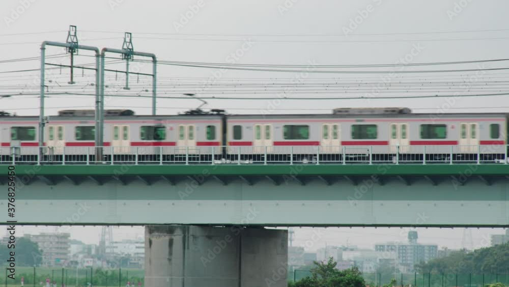 JR Train Travels Across The Metro Rail Bridge In Tamagawa River Tokyo, Japan During Misty Morning. - Tripod Shot JR Train Travels Across The Metro Rail Bridge In Tamagawa River Tokyo, Japan During Misty Morning. - Tripod Shot