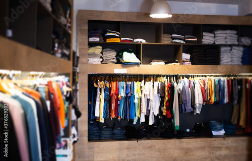 Variety of modern male wear on hangers and shelves in clothing showroom