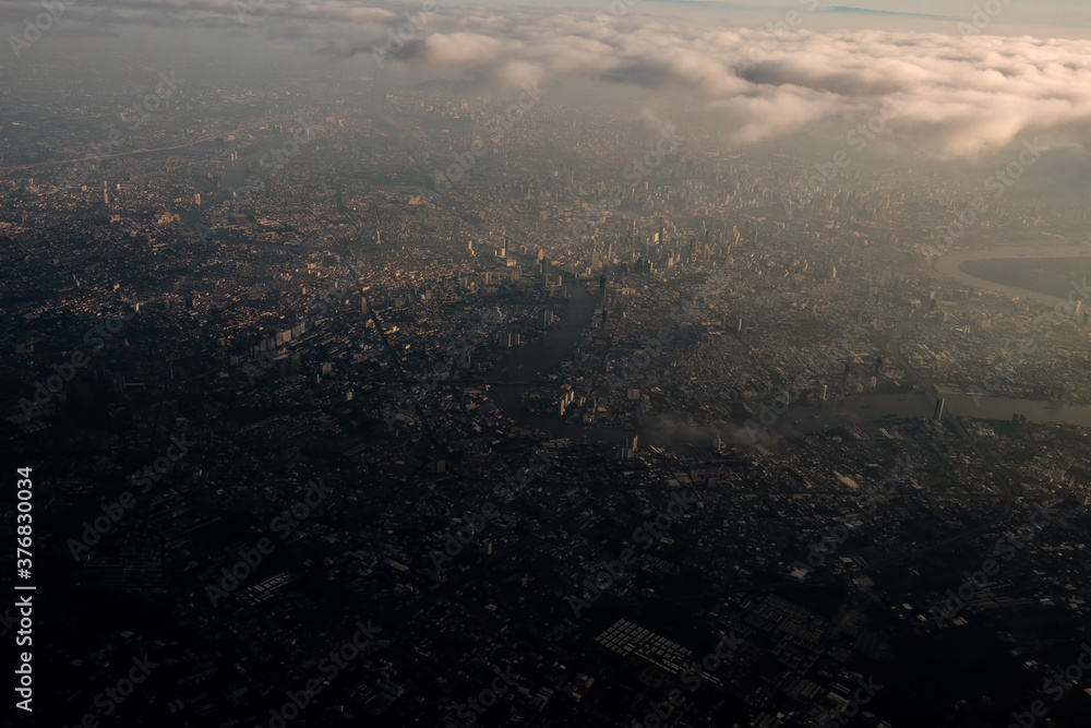 Fototapeta premium Bangkok city's bird eye view shot from a plane that flight in a morning with warming color of sunrise and some shade from clouds .photo may had some noise and partly blur