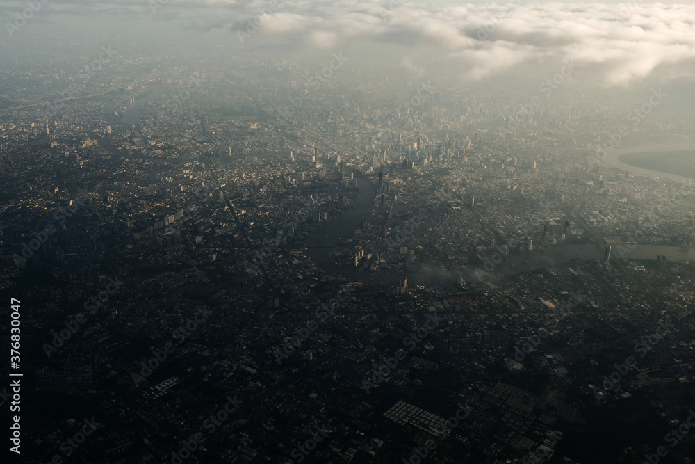 Bangkok city's bird eye view shot from a plane that flight in a morning with warming color of sunrise and some shade from clouds .photo may had some noise and partly blur