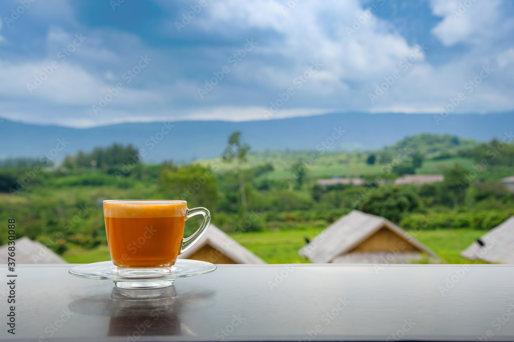 hot Thai's style milk tea in a cup with mountain view when a raining is coming from somewhere faraway
