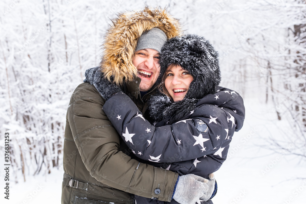 Obraz premium Young couple in love have fun in the snowy forest. Active winter holidays.
