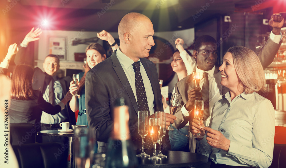 Glad man and woman drinking alcohol and having conversation on corporate party