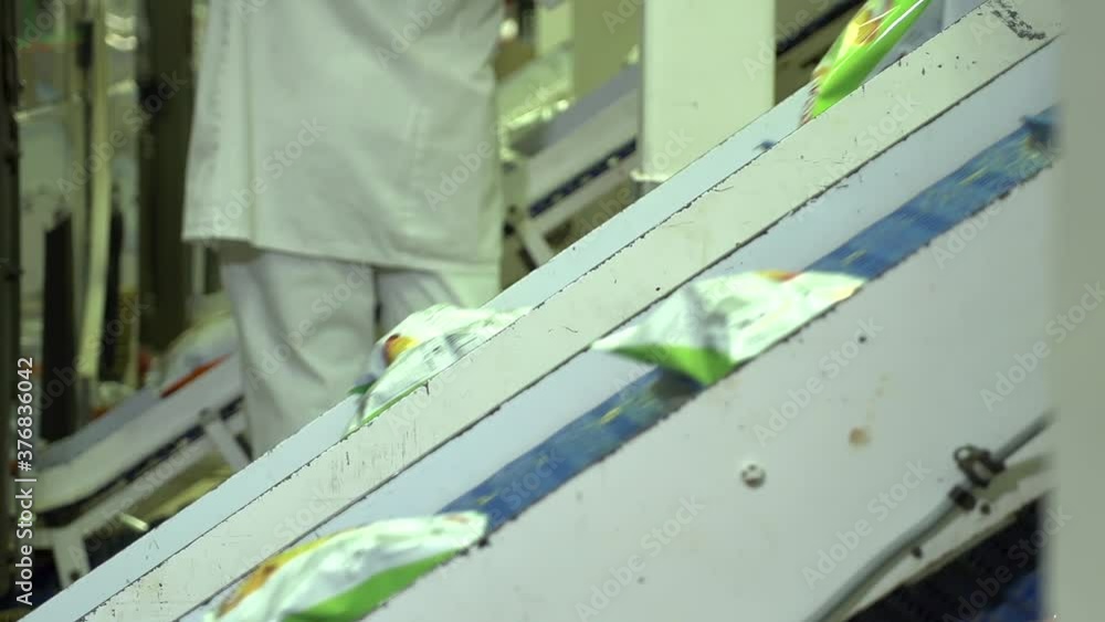 Multiple conveyor belts of packaged potato snack foods ready for boxing at manufacturing plant. Multiple conveyor belts of packaged potato snack foods ready for boxing at manufacturing plant.