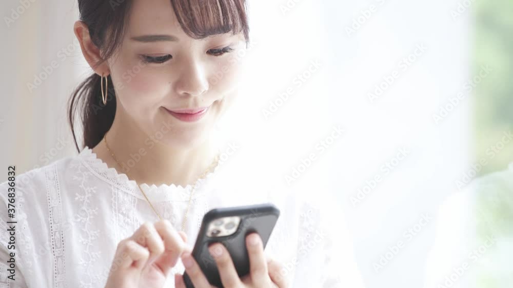 スマートフォンを操作している若い女性 スマートフォンを操作している若い女性