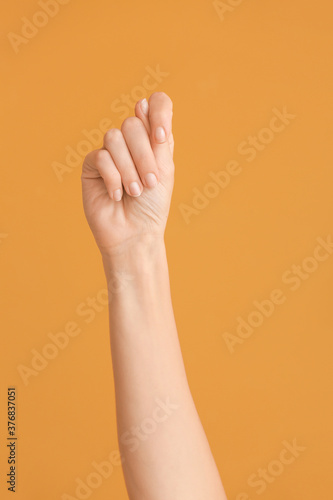 Hand showing letter T on color background. Sign language alphabet