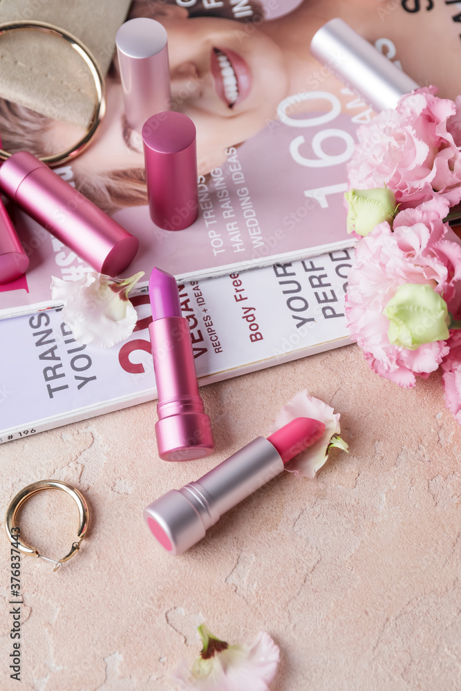 Naklejka premium Different lipsticks, fashion magazines and bijouterie on table