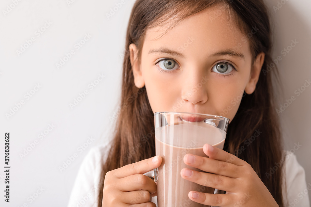 Little girl drinking tasty chocolate milk on light background Little girl drinking tasty chocolate milk on light background