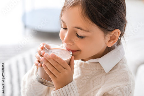 Little girl drinking tasty chocolate milk at home