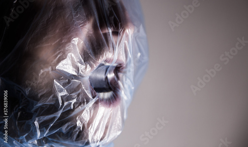 Human suffocating in plastic bag. Plastic pollution problem themed image. STOP using plastic!  photo