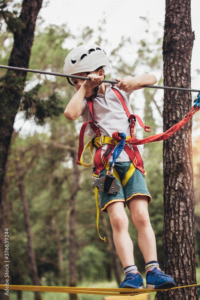 Happy child enjoying activity in a climbing adventure park on a summer day Happy child enjoying activity in a climbing adventure park on a summer day