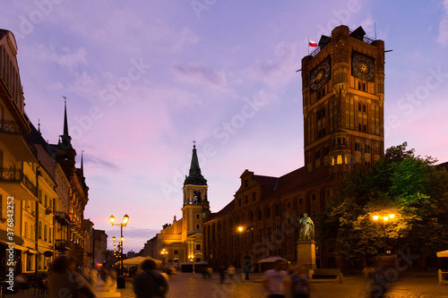 Illuminated streets of Torun with Town Hall and statue of Nicolaus Copernicus in evening © JackF