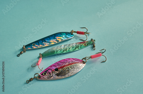 Fishing equipment. Three metal fishing lures on a blue background