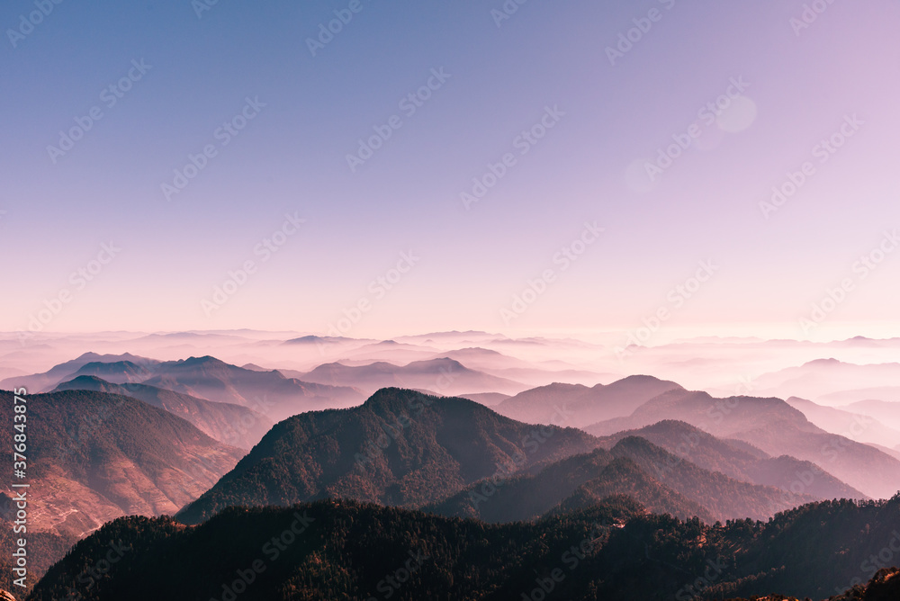 View of Himalayas mountain range with visible silhouettes through the colorful fog from Khalia top trek trail. Khalia top is at an altitude of 3500m himalayan region of Kumaon, Uttarakhand, India. View of Himalayas mountain range with visible silhouettes through the colorful fog from Khalia top trek trail. Khalia top is at an altitude of 3500m himalayan region of Kumaon, Uttarakhand, India.