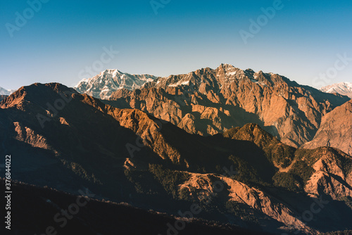 Panoramic view of Snow cladded peaks falls in great Himalayan mountain range and alpine grass meadows at small hamlet Munsiyari, Kumaon region, Uttarakhand, India.