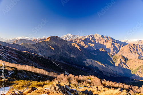 Panoramic view of Snow cladded peaks falls in great Himalayan mountain range and alpine grass meadows at small hamlet Munsiyari, Kumaon region, Uttarakhand, India.