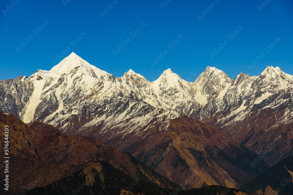 Obraz premium View of Snow cladded Panchchuli peaks falls in great Himalayan mountain range & alpine grass meadows enroute to Khalia Top trekk trail at small hamlet Munsiyari, Kumaon region, Uttarakhand, India.