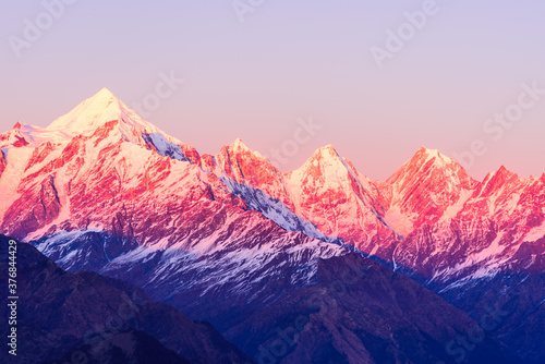 Panoramic view during sunset over snow cladded Panchchuli peaks falls in great Himalayan mountain range from small hamlet Munsiyari, Kumaon region, Uttarakhand, India. photo