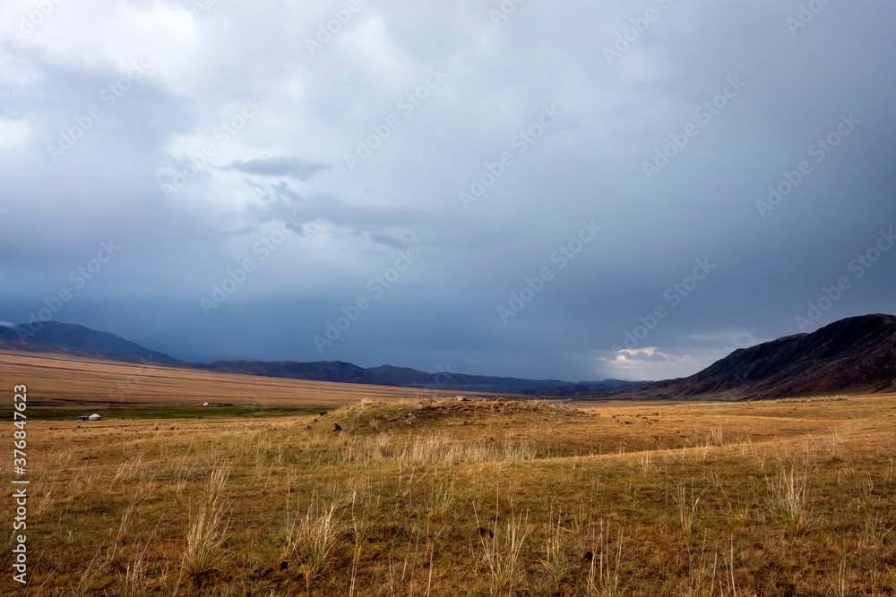 Mountain plateau with ancient mound and cloudy blue sky on background. Rural scenery. Summer nature landscape. Borokhudzir plateau, Kazakhstan. Tourism in Kazakhstan concept.