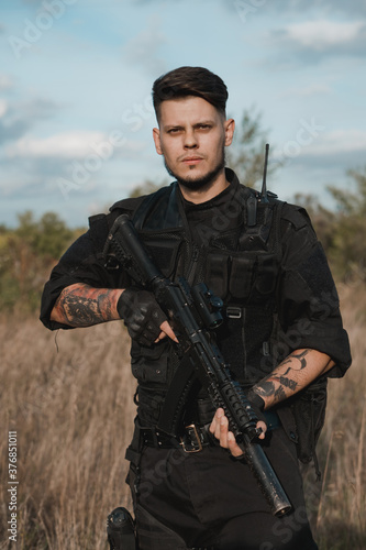 Young soldier in black uniform with an assault rifle.