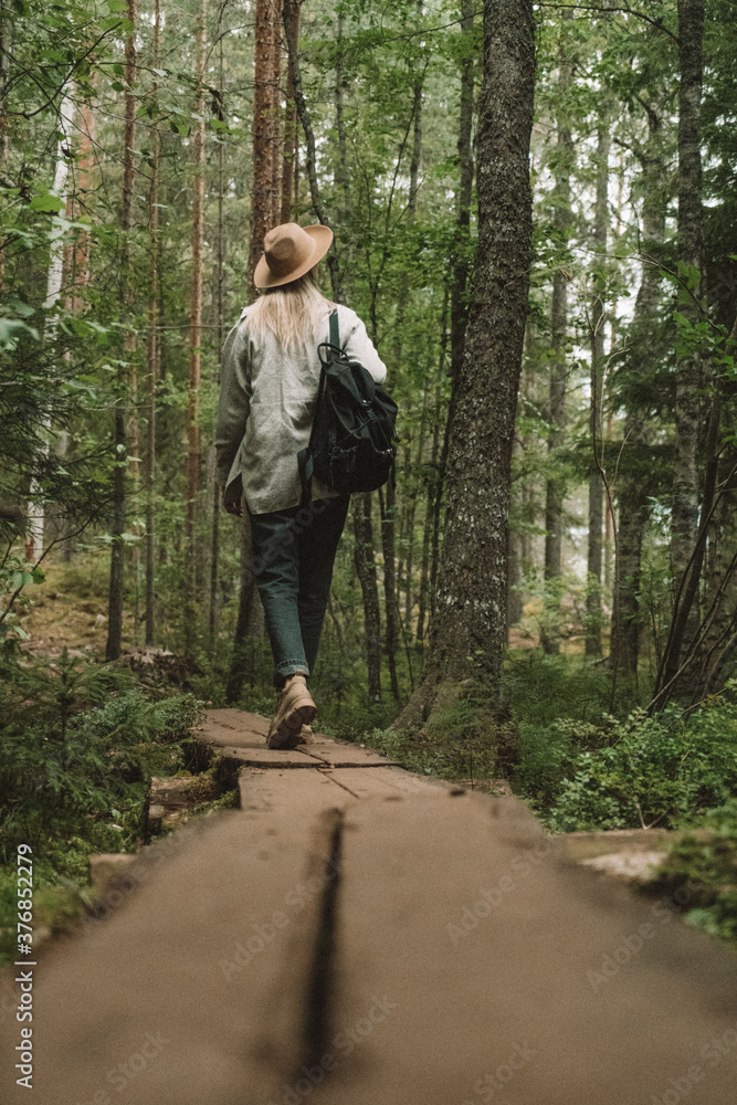 Women girl walking on the wooden path in the forest of Finland in National Part Women girl walking on the wooden path in the forest of Finland in National Part