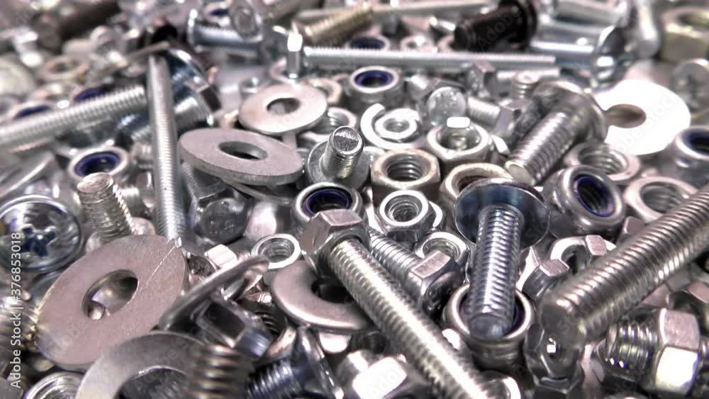 Video showing the passage of bolts, nuts and washers isolated on a steel sheet. Metal fasteners. Video showing the passage of bolts, nuts and washers isolated on a steel sheet. Metal fasteners.