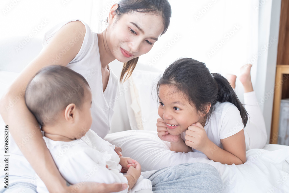 happy loving family. Love, trust and tenderness concept. Mother and child on a white bed. Parent and little kid relaxing at home. Mother and her daughters children girls playing and hugging.