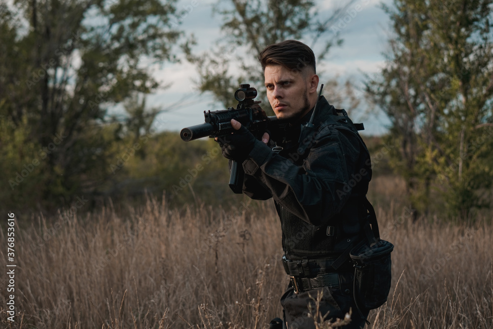 Young soldier in black uniform aiming an assault rifle. Copy space. Young soldier in black uniform aiming an assault rifle. Copy space.