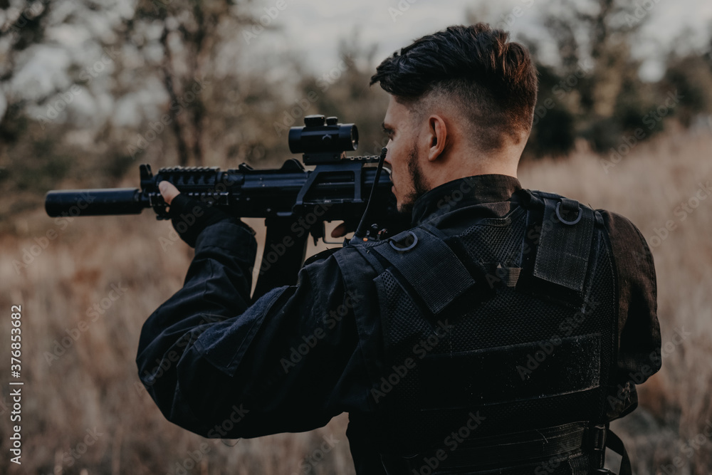 Young soldier in black uniform aiming an assault rifle. Young soldier in black uniform aiming an assault rifle.