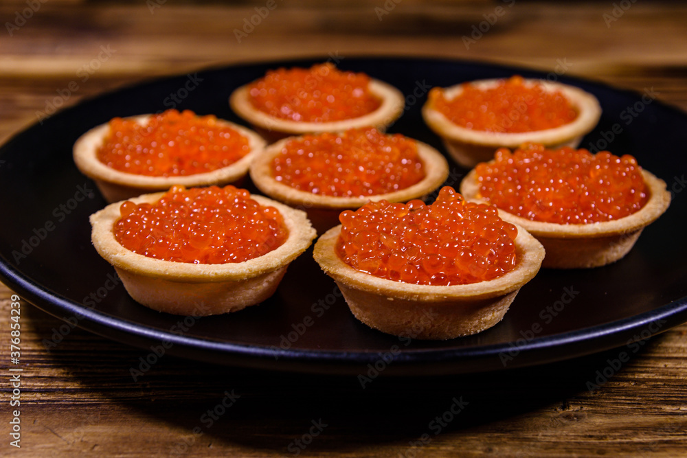 Tartlets with red caviar on a black plate. Festive food Tartlets with red caviar on a black plate. Festive food