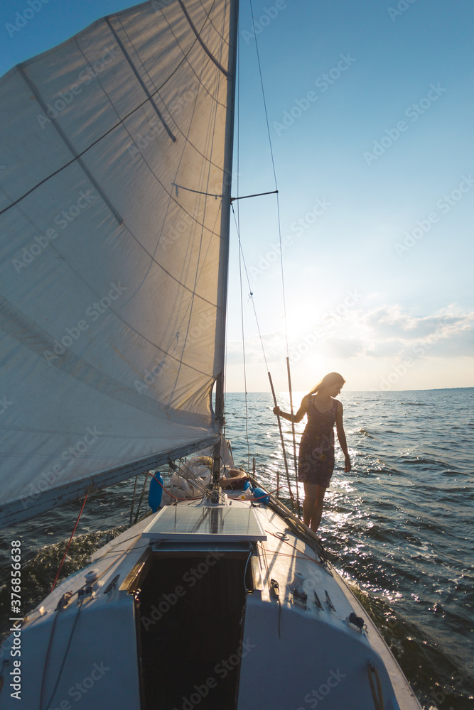 Fototapeta premium A girl in a dress stands on a sailing yacht