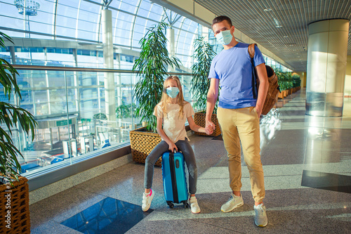 Dad and little girl with nedical masks at airport. Protection against Coronavirus and gripp