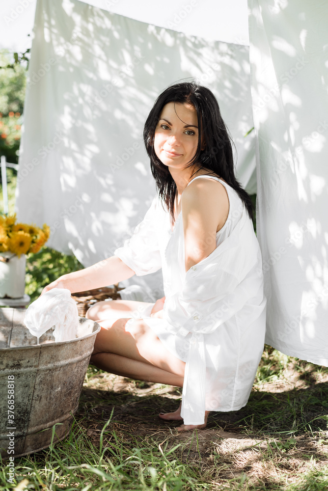 The brunette girl washes clothes in the country. Retro style. Photoshoot washing clothes The brunette girl washes clothes in the country. Retro style. Photoshoot washing clothes