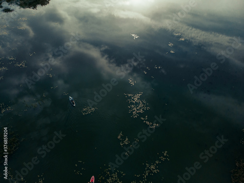 Top view of tourists on lake with SUP-boards. Beautiful clear water with people floating on boards engaged in sup-surfing. Seascape with people rowing on boards on background horizon photo