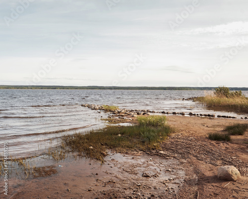 Huge stones on the river bank. Vuoksa river near Imatra in the Leningrad region, Russia. Coastline with birch, pine tree forest reflected in Vuoksa water, near Finland.