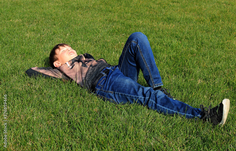 Teenage boy lying on the grass in a park on sunny autumn day Teenage boy lying on the grass in a park on sunny autumn day