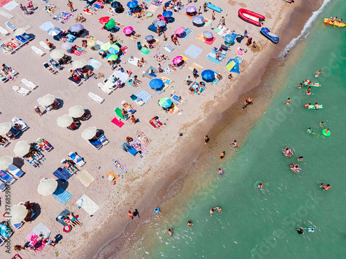 Aerial View Of People And Colorful Umbrellas On Ocean Seaside Beach In Summer