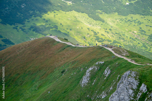 Long and curved hiking trails through the red peaks in Tatra Mountains in Poland during hot summer day.