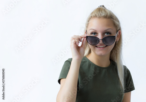 portrait of a girl with blond hair on an isolated white background holds sunglasses in her hand  looks into the distance  dreams of rest