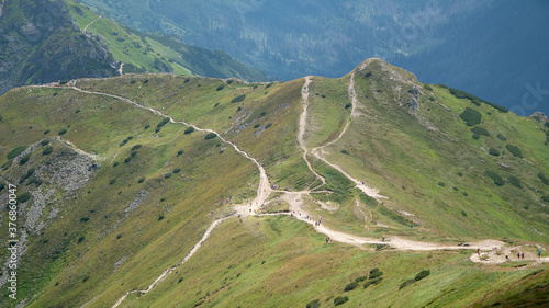 Long and curved hiking trails through the red peaks in Tatra Mountains in Poland during hot summer day.