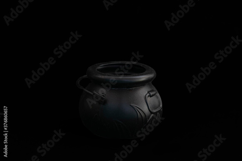 Black witch's cauldron on a black background. Design for halloween. The photo