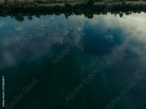 Top view of tourists on lake with SUP-boards. Beautiful clear water with people floating on boards engaged in sup-surfing. Seascape with people rowing on boards on background horizon