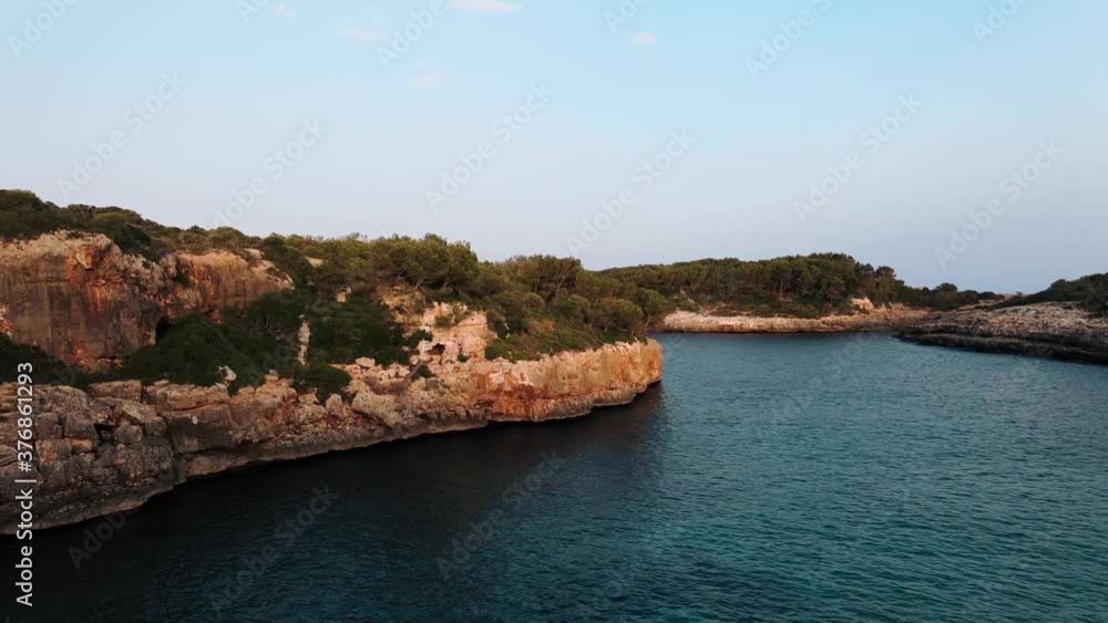 Aerial view flying towards low cliffs with vegetation on the coastline at golden hour Aerial view flying towards low cliffs with vegetation on the coastline at golden hour