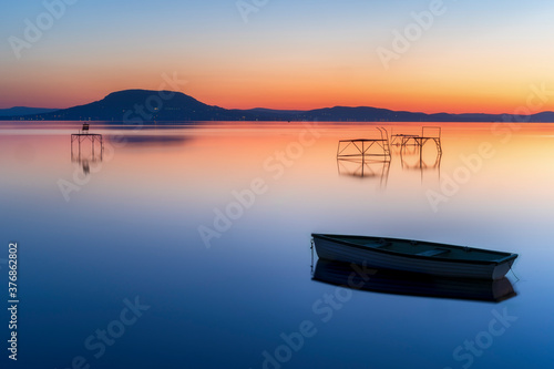 Relaxing and calm sunrise at lake balaton in hungary. Boat and fisher posts. Mountain Badacsonyi and city Badacsony photo