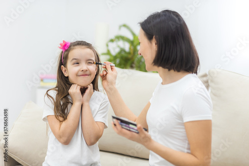 Photo of mother and daughter putting on make up in the living room.