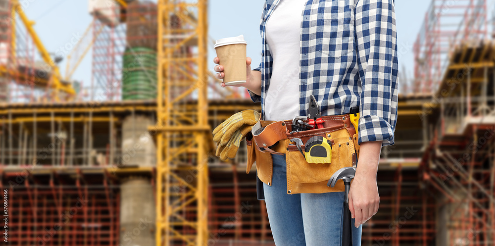 building, construction and job concept - woman or builder with takeaway coffee cup and working tools on belt over background building, construction and job concept - woman or builder with takeaway coffee cup and working tools on belt over background