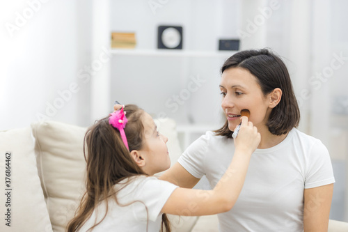 Photo of adorable little girl playing with mommy's make up products.