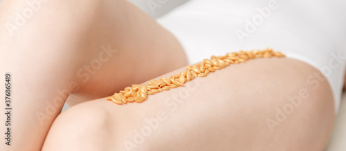 Wax beans or seed in row on legs of young woman lying on white background