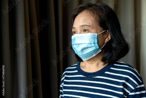 Portrait of Asian elder senior old female wearing face medical mask. pandemic coronavirus disease quarantine in home. Covid-19 outbreak prevention concept.
