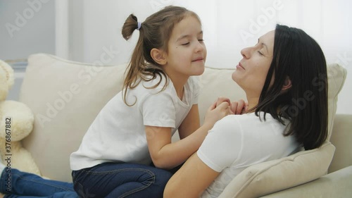 4k slowmotion video of lovely mother and beautiful daughter sitting on the sofa. photo